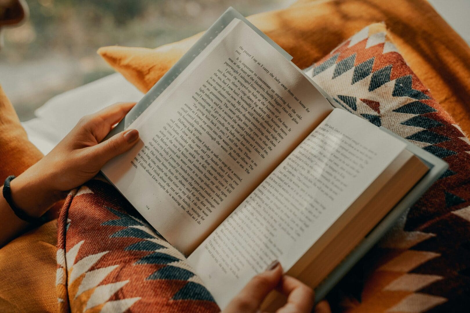 A person is reading an open book on the couch