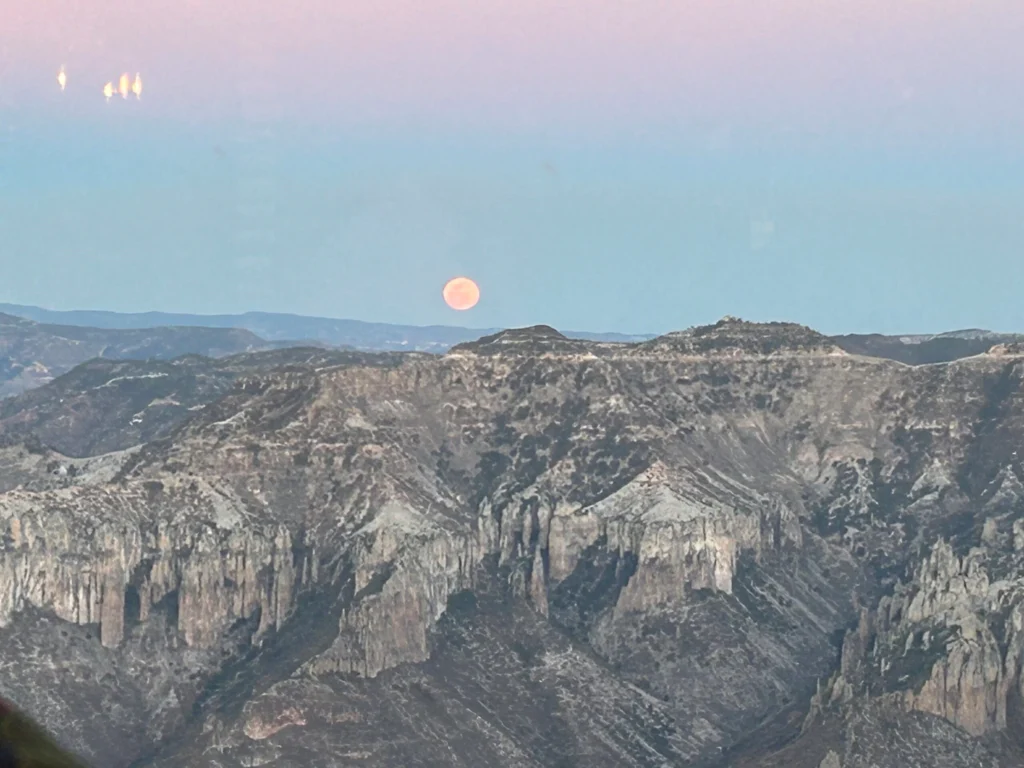 A full moon setting over the mountains.