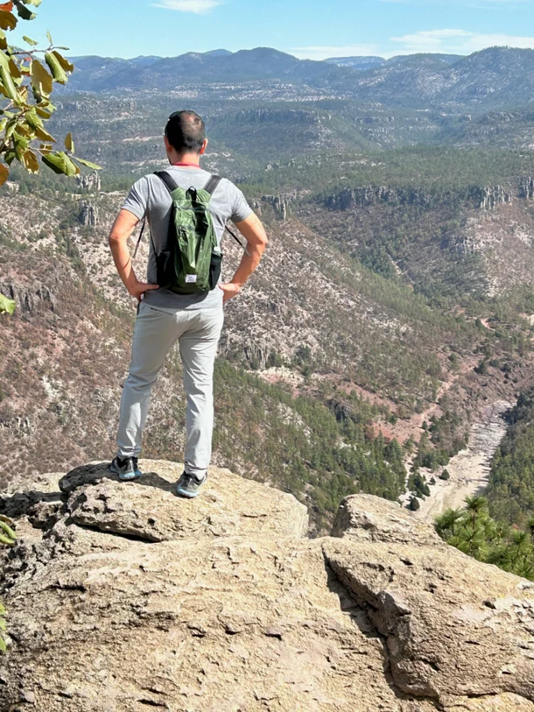 A man standing on top of a mountain looking at the view.